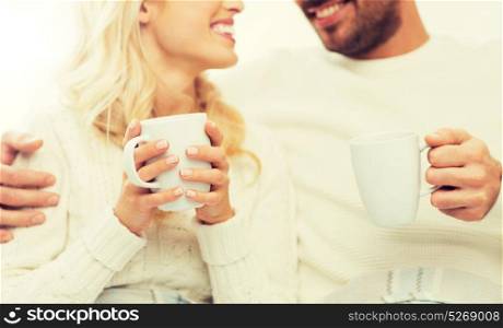winter, love, family and happiness concept - close up of happy couple with tea cups at home. close up of happy couple with tea cups at home