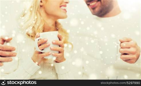 winter, love, family and happiness concept - close up of happy couple with tea cups at home. close up of happy couple with tea cups at home