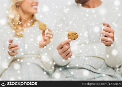 winter, love, food and sweets concept - close up of happy couple with oat cookies and tea cups at home