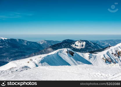 Winter mountain landscape. Caucasus ridge covered with snow in sunny day. Krasnaya Polyana, Sochi, Russia