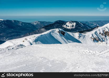 Winter mountain landscape. Caucasus ridge covered with snow in sunny day. Krasnaya Polyana, Sochi, Russia