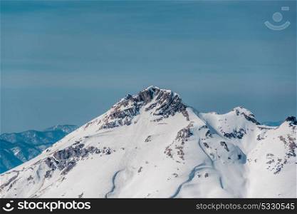 Winter mountain landscape. Caucasus ridge covered with snow in sunny day. Krasnaya Polyana, Sochi, Russia
