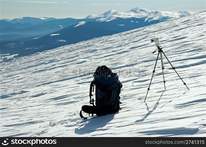 Winter mountain landscape with tourist knapsack and photographic tripod (Ukraine, Carpathian Mt&rsquo;s, Goverla and Petros Mountains behind)