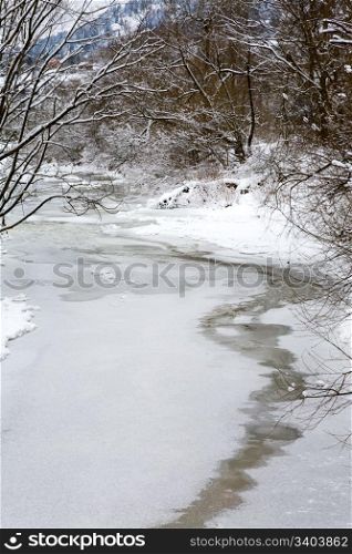 winter mountain river with rime covered trees and bushes on riverside