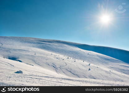 Winter mountains landscape with shining sun on bright blue sky