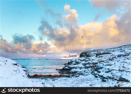 Winter Norway. Lofoten. The clouds over the bay with the islands. The rocky coast is covered with snow. Clouds over the Winter Bay