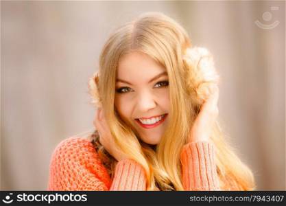 Winter or autumn fashion ear protection. Portrait lovely girl in warm clothes. Happy woman in earmuffs walking in foggy day autumnal park, outdoors