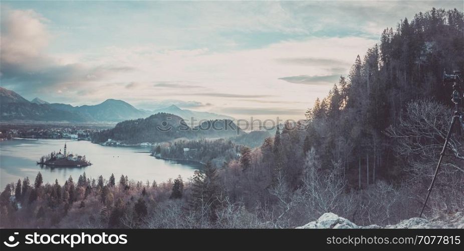 Winter panorama at sunrise with the Bled lake and village, surrounded by the Julian Alps and a camera mounted on a tripod