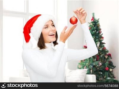 winter, people, christmas and happiness concept - woman in santa helper hat with christmas tree decoration ball over living room and christmas tree background