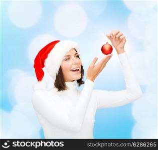 winter, people, christmas and happiness concept - woman in santa helper hat with christmas tree decoration ball over blue lights background