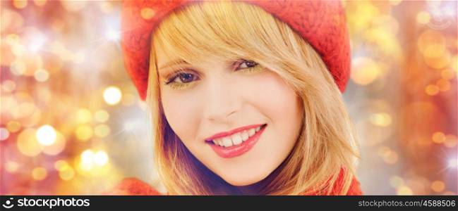 winter, people, christmas and holidays concept - close up of happy smiling woman in red hat and scarf over lights background
