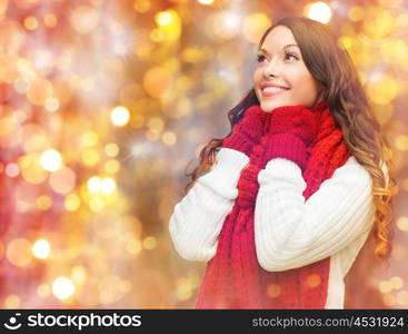 winter, people, christmas and holidays concept - happy smiling woman in scarf and mittens over lights background