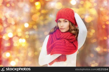 winter, people, christmas and holidays concept - woman in hat, muffler and pullover over lights background
