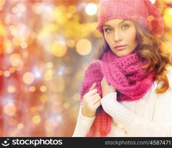 winter, people, christmas and holidays concept - woman in hat, muffler and pullover over lights background