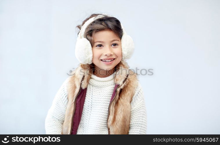 winter, people, happiness concept - happy little girl wearing earmuffs