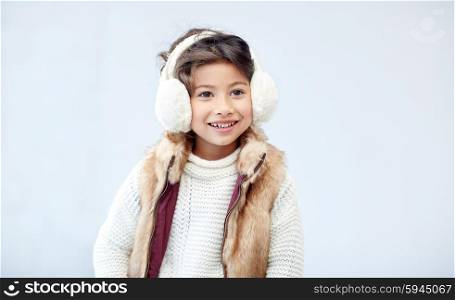 winter, people, happiness concept - happy little girl wearing earmuffs
