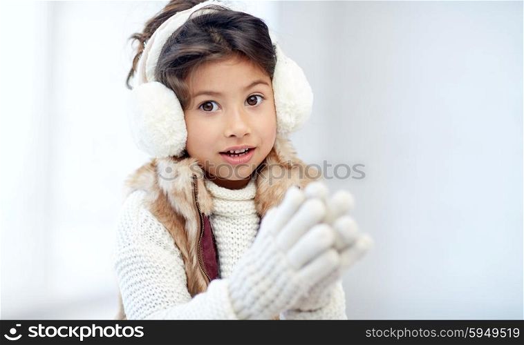 winter, people, happiness concept - happy little girl wearing earmuffs