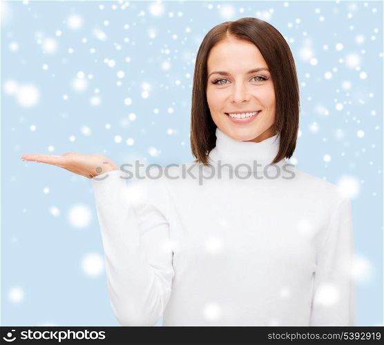 winter, people, happiness concept - smiling woman in white sweater with something on palm