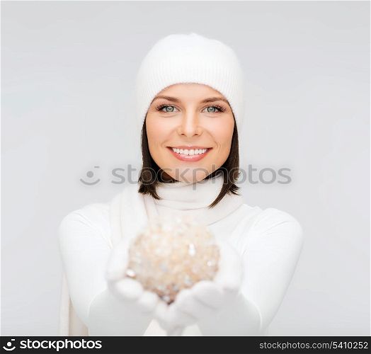 winter, people, happiness concept - woman in hat, muffler and gloves with christmas decoration ball