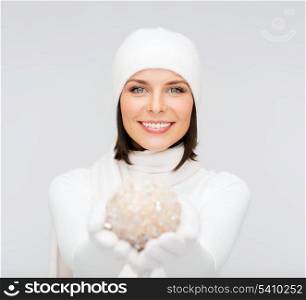 winter, people, happiness concept - woman in hat, muffler and gloves with christmas decoration ball