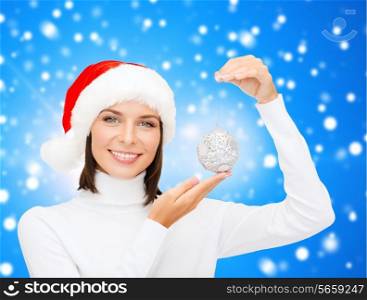 winter, people, happiness concept - woman in santa helper hat with christmas tree decoration over blue snowy background