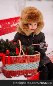 Winter portrait of a child on a bench.. A child with a basket sits on a red bench in winter 3126.