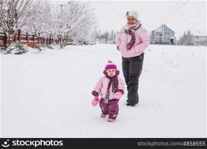 Winter portrait of grandmother with a granddaughter in the yard. Grandmother with granddaughter for a walk