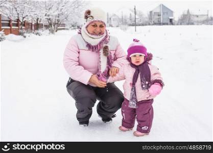 Winter portrait of grandmother with a granddaughter in the yard. Grandmother with granddaughter for a walk