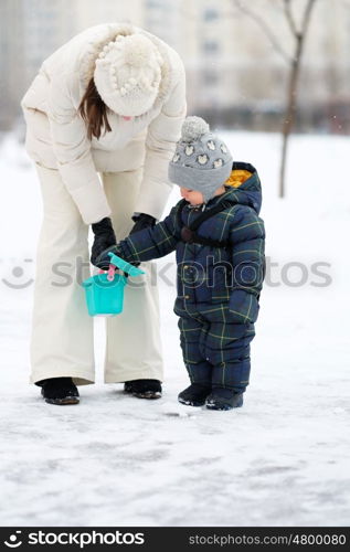 Winter portrait of toddler boy with mother in warm coat outdoors