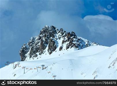Winter rocky mount top (Tyrol, Austria) and ski lift on slope.
