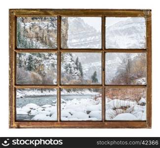 Winter scenery of mountain river in deep canyon as seen through vintage, grunge, sash window with dirty glass
