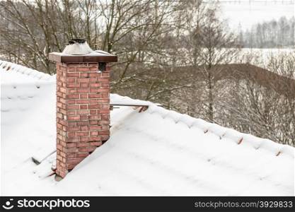 Winter season and seasonal specific. Red chimney and roof covered with snow
