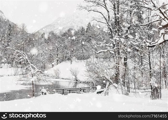 Winter Snowy Bavarian Alpine landscape with snow covered field, house and trees. Magic wintry scenery background at snowfall. Germany, Europe. Monochromatic neutral tones with natural light