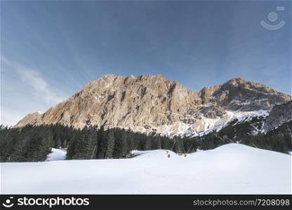 Winter snowy landscape with snow-covered peaks of the Alps mountains, fir forest and snow layer in Ehrwald, Austria, on a sunny day of December.