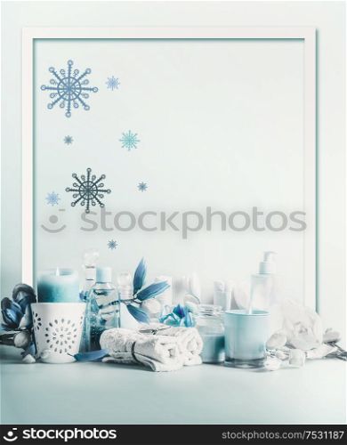 Winter spa and wellness concept. Winter skin and body care. Cosmetic products. Holiday spa day. Frame. Blue composition of candles, towels, and flowers. Winter beauty