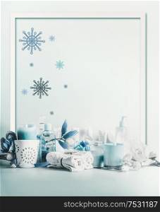 Winter spa and wellness concept. Winter skin and body care. Cosmetic products. Holiday spa day. Frame. Blue composition of candles, towels, and flowers. Winter beauty