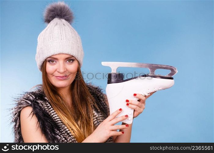 Winter, sport, people concept. Beautiful girl with white skate. Young lady has cap and fur vest.. Young lady has cap and fur vest.