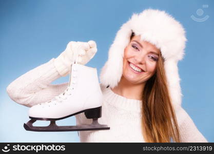 Winter sports clothing concept. Attractive lady with ice skate. Young woman wearing white cozy outfit on blue. Attractive lady with ice skate.