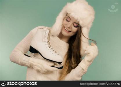 Winter sports clothing concept. Attractive lady with ice skate. Young woman wearing white cozy outfit. Attractive lady with ice skate.