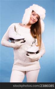 Winter sports clothing concept. Attractive lady with ice skate. Young woman wearing white cozy outfit.. Attractive lady with ice skate.