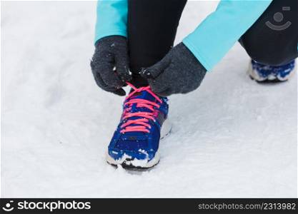 Winter sports fashion concept. Tying sport fitness shoes in snow, footwear for workout outside. Tying sport shoes in snow