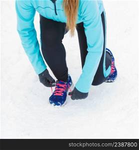 Winter sports fashion concept. Tying sport fitness shoes in snow, footwear for workout outside. Tying sport shoes in snow