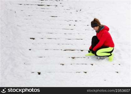 Winter sports fashion concept. Woman tying sport fitness shoes in snow, footwear for workout outside. Woman tying sport shoes during winter