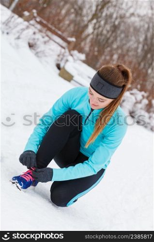 Winter sports fashion concept. Woman tying sport fitness shoes in snow, footwear for workout outside. Girl tying shoelaces, winter footwear