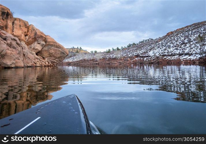 winter stand up paddling on a calm lake at Colorado foothills (Horsetooth Reservoir), POV from paddleboard bow
