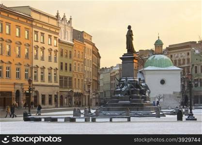 Winter sun on the buildings in the Market Square ( Rynek Glowny) with St Adalbert&rsquo;s Church and the Statue of Adam Mickiewicz, looking south towards Grodzka in the city of Krakow in Poland.