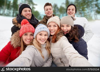 winter, technology, friendship and people concept - group of smiling men and women taking selfie outdoors