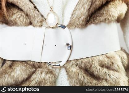 Winter time fashion for women. Woman wearing sweater fur vest belt and pendant in freezing cold time.