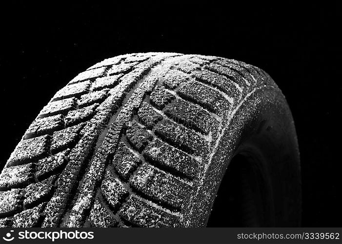 Winter tyre cover in snow on a black background