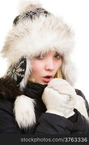 Winter vacation. Freezing girl in warm clothes. Young woman in fur hat warming her cold hands by breath isolated on white.